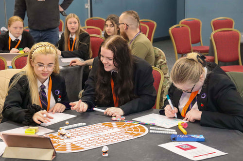 Group of students and teachers participating in a classroom activity with educational materials.