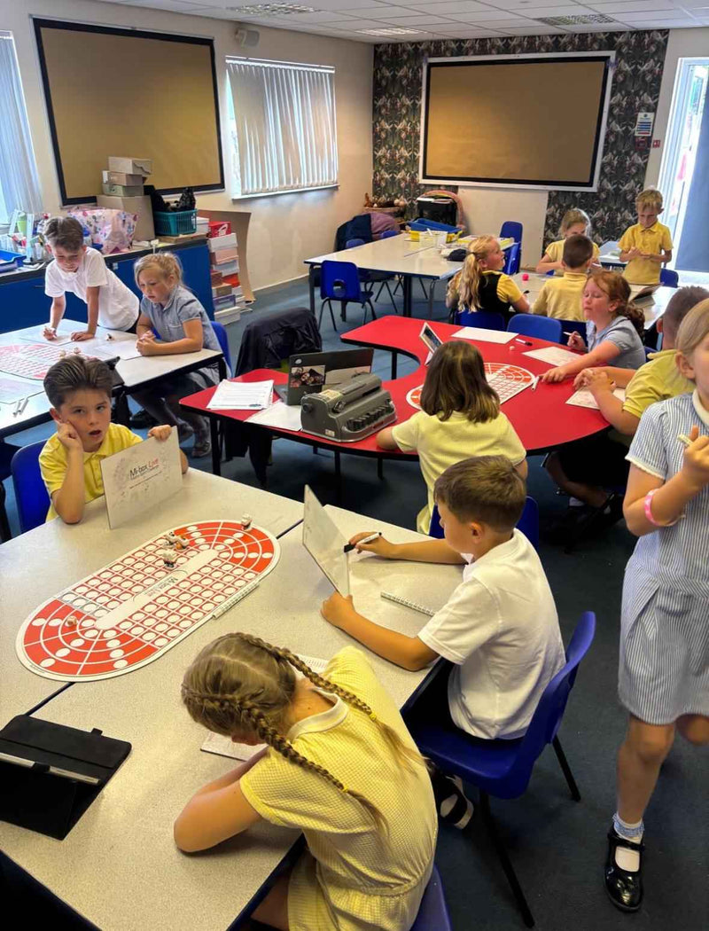 Children in a classroom setting with educational materials and computers.